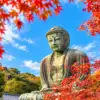 The bronze Great Buddha of Kamakura framed by red and orange autumn leaves.