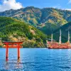 A pirate-style sightseeing ship on Lake Ashi beside a red torii gate and wooded hills.