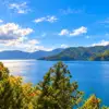 Blue water at Lake Chuzenji bordered by forested mountains and autumn-coloured trees.