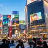 Crowds and illuminated advertising screens around Shibuya Crossing in Tokyo.