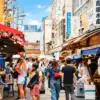 Shoppers walking between food stalls and shopfronts at Tsukiji Outer Market in Tokyo.